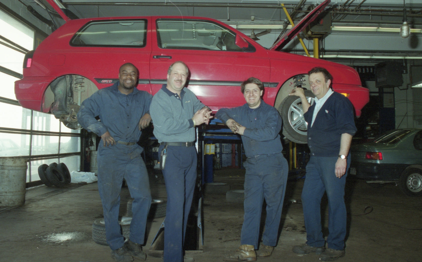 Garagistes posant devant une auto en réparation